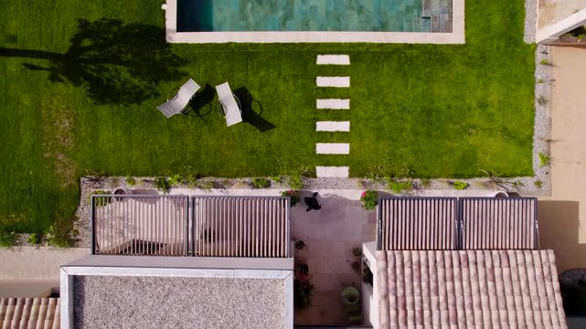 Aerial view of woman walking in beautiful modern villa garden by private pool.