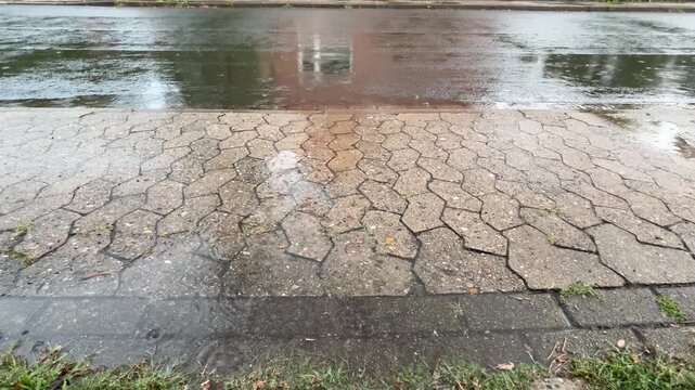 Rainwater puddle with building reflections and raindrop ripples on wet paving stones