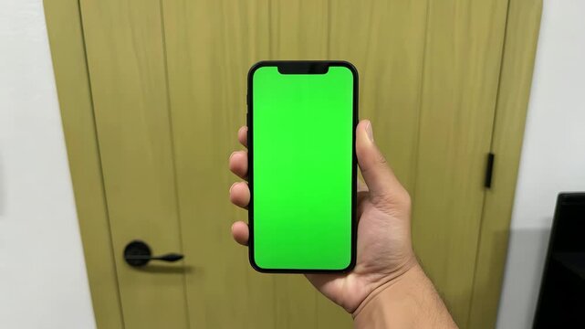 Hand holding modern smartphone with bright green chroma key screen in this high quality vertical motion video clip for editing