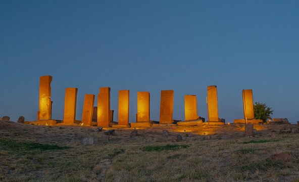 Row of historical Seljuk tombstones illuminated under the blue hour sky after sunset in the ancient Ahlat Seljuk Cemetery, Bitlis, Turkey. Long exposure shot highlighting medieval Islamic funeral arch
