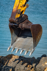 a closeup of a excavator bucket in the sand © George