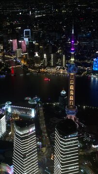 Oriental Pearl Tower glows with changing illumination above the illuminated Shanghai financial district and Huangpu River at night, captured in timelapse