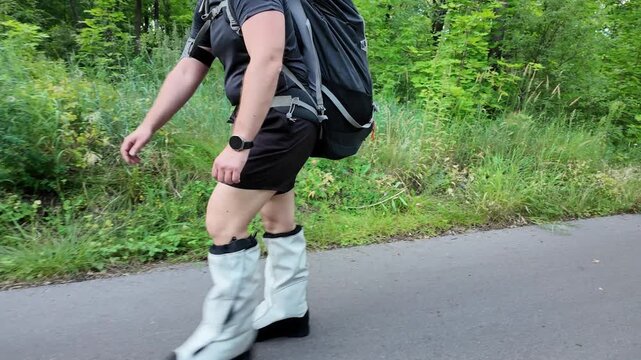 A man embarks on a challenging training session for mountaineering in a lush forest. He carries a 50 kg backpack, donning sturdy climbing boots as he navigates the trail.