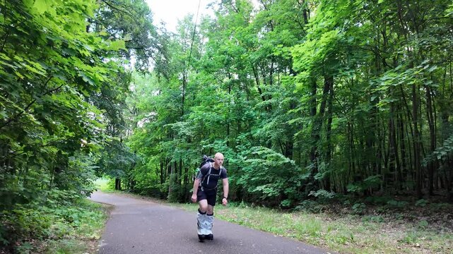 A dedicated man hikes through a lush forest trail, carrying a 50 kg backpack. Dressed in climbing boots, he trains hard to prepare for his upcoming mountaineering challenge.