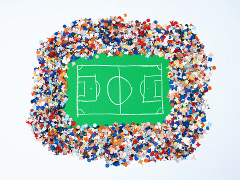 Chalk Hand Drawn Soccer Pitch on Green Paper Framed by Colorful Confetti Representing a Packed Stadium Crowd