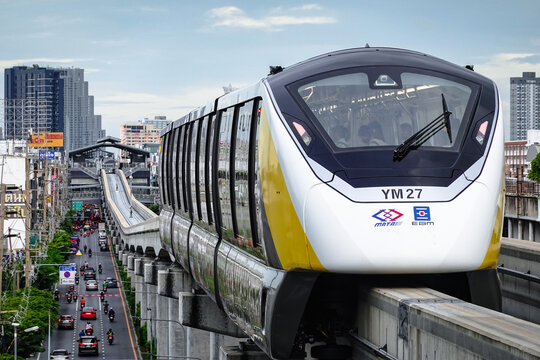 Bangkok, Thailand  August 17, 2026: The Yellow Line skytrain serves the public, tourists, and commuters at Mahat Thai Station during rush hour amidst heavy traffic on Lat Phrao Road,