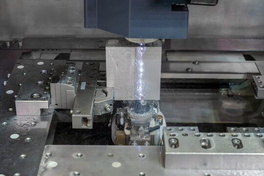 Wire electrical discharge machining of a metal workpiece with precision cutting wire and dielectric fluid in an industrial workshop