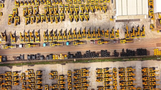 Yellow construction machinery lined up at heavy equipment manufacturing plant with passing cloud shadows industrial