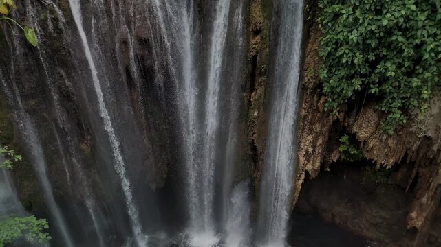 Breathtaking Waterfall Cascading Over Moss-Covered Rocks Surrounded by Lush Greenery