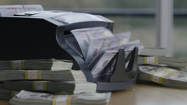 closeup shot of money counting machine with 100 dollar bills