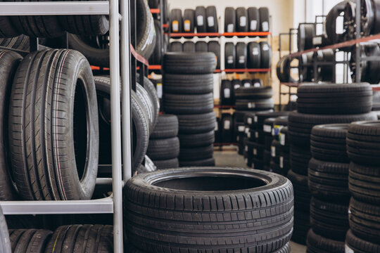 Rows of rubber car tires stored on metal racks and stacked high in an auto repair shop, preparing for vehicle maintenance