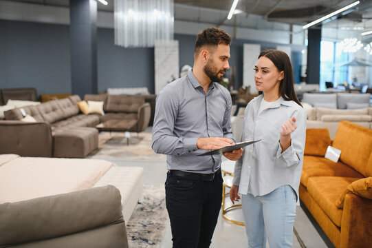 Sales consultant helping woman choose furniture in store