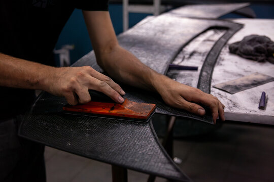 craftsman sands a car part with a sanding block
