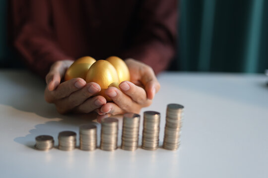 Rising stack of coins on the table and golden eggs on businessman's hand. Concept for financial planning and investment return.