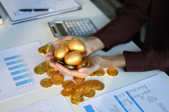 Gold coins and golden eggs in businessman&rsquo;s hands. Concept for financial growth and investment.