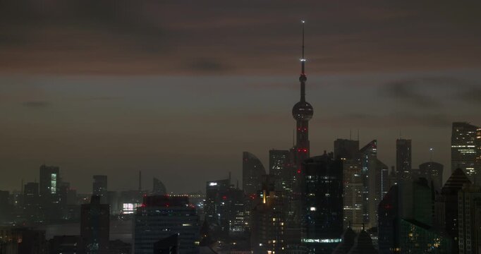 Morning sun rises behind the Oriental Pearl Tower and Pudong skyline as night transitions to dawn over Shanghai, recorded in timelapse