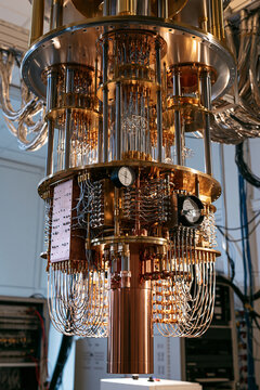 Goldener Quantencomputer mit komplexer K&uuml;hltechnik im Labor, warmes Licht, realistisch, geeignet f&uuml;r Wissenschaftspr&auml;sentation und Technologiebericht.