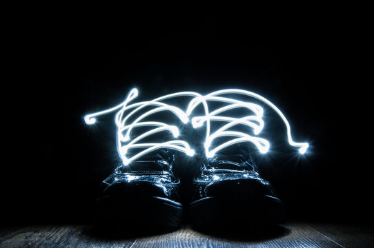 Black shoes with illuminating shoelaces on black background