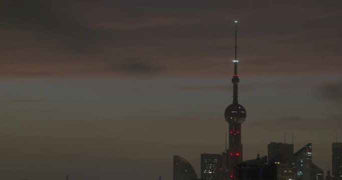 Night turns to bright morning as the sun rises over Oriental Pearl Tower and Pudong skyscrapers in Shanghai, filmed in timelapse