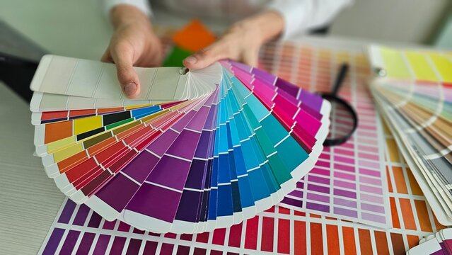 Color samples are arranged in a fan shape in hands during a design activity
