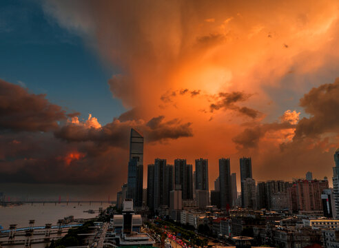 Dramatic sunset over the Wuhan skyline and Yangtze River. This fiery sky features "virga" phenomenon, where falling rain catches golden light, creating a stunning illusion of burning clouds.	
