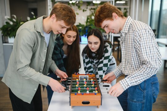 Coworkers playing table football in the office during break time