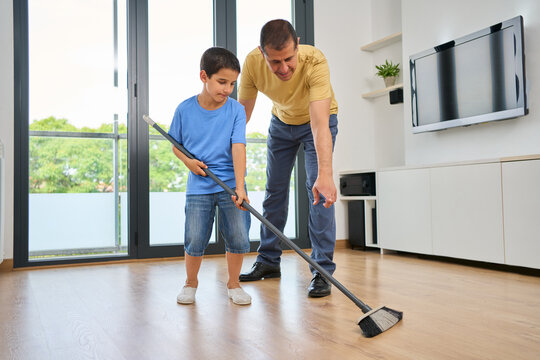 Father and kid sweeps in home for household chores, development and learning responsibility. People, housework tasks and floor maintenance for support, bonding and dirt removal at home