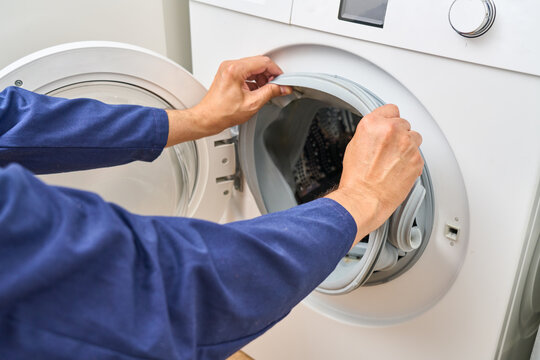 Person repairs a washing machine by removing the old door seal.