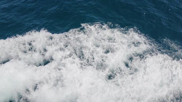 Close-up of white boat wake and sea foam churning across blue water, Cote d'Azur, France