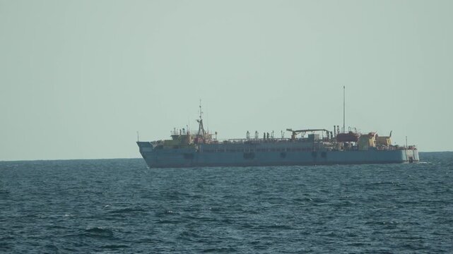 Ship, ocean, vessel, a large grey industrial ship sails on the calm open sea under a clear sky
