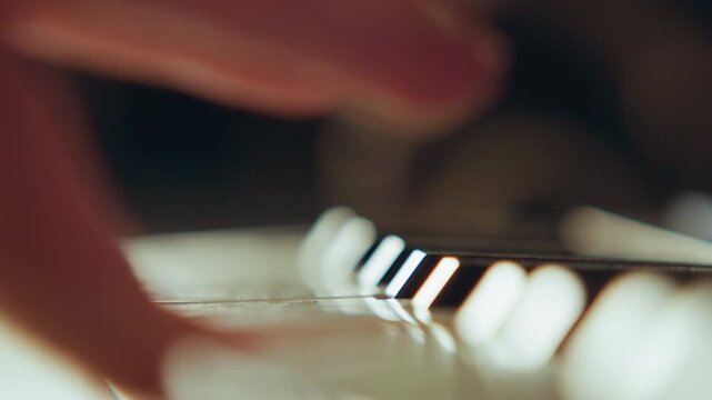 Close low-angle view of fingers pressing and sweeping across keyboard keys with visible motion blur on fingertips and key edges, showing active typing, warm lighting, glossy surfaces, and focused