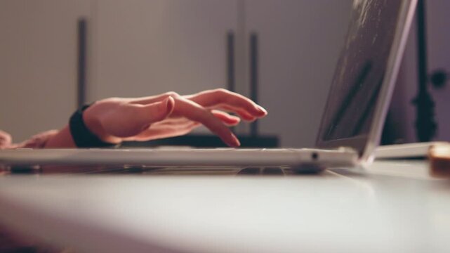 Close-up low-angle view of hands poised above laptop keyboard, fingers curved and slightly elevated, conveying active typing motion, focused work, and ready input in soft indoor light