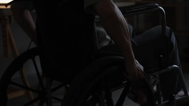 Close up of senior man gripping wheelchair wheel with hand to move independently.