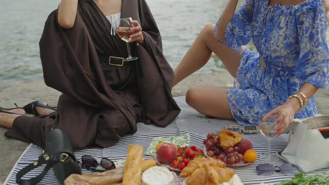 Close-up of women holding wine at a Paris Seine picnic