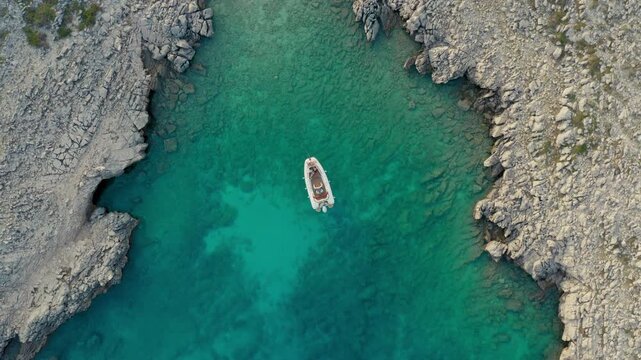 aerial view of a couple relaxing on a motorboat in a serene bay clear water in a lu