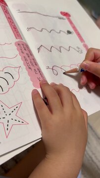 ワークで線を書く練習をする子供の手