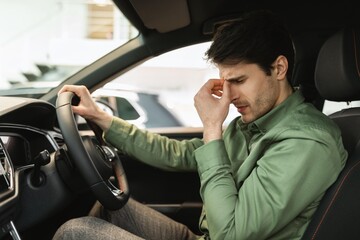 Worried Young Caucasian Man Driving Car, Showing Stress Expression While Holding Steering Wheel,...