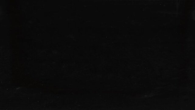 Scratches and dust dark grunge paper background. Scratched damaged dynamic overlay texture surface in trendy vintage stop motion style. 4k black grunge gritty abstract background loop animation.