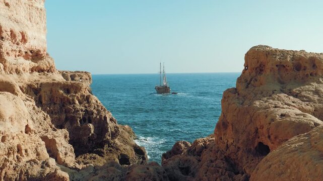 amazing slow motion shot of pirate boat sailing in the middle of two rocks on a sun