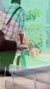 Animation of hands using tablet, over man arriving at creative office with bike