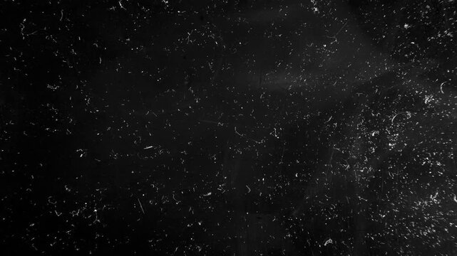 Scratches and dust dark grunge paper background. Scratched damaged dynamic overlay texture surface in trendy vintage stop motion style. 4k black grunge gritty abstract background loop animation.
