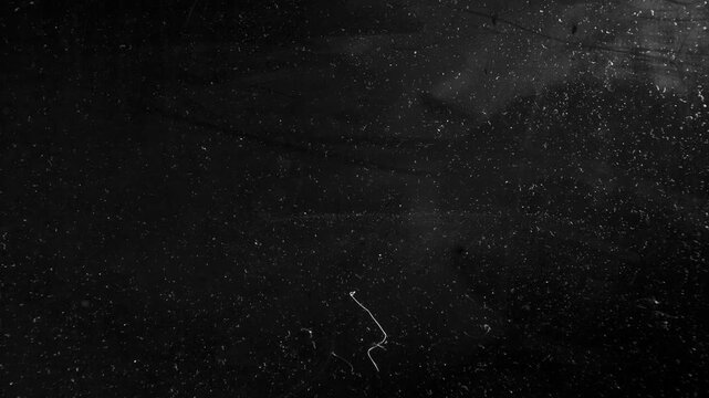 Scratches and dust dark grunge paper background. Scratched damaged dynamic overlay texture surface in trendy vintage stop motion style. 4k black grunge gritty abstract background loop animation.