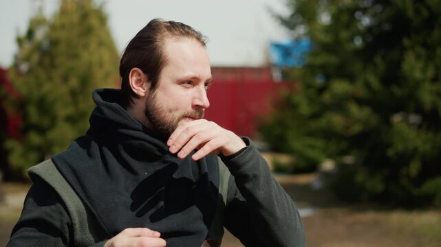 Medium close-up of man standing outdoors in winter clothing, dark scarf wrapped around neck, jacket visible, short beard, tied-back hair, speaking with calm reflective expression, with man, portrait