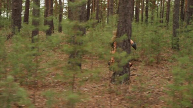 Woman in rust skirt runs laterally across dense pine forest understory, midstride with billowing fabric, raised arm, layered trunks, and swaying branches, conveying adventurous outdoor motion