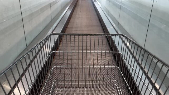 Empty Shopping Cart going up a glass escalator with natural light coming in.