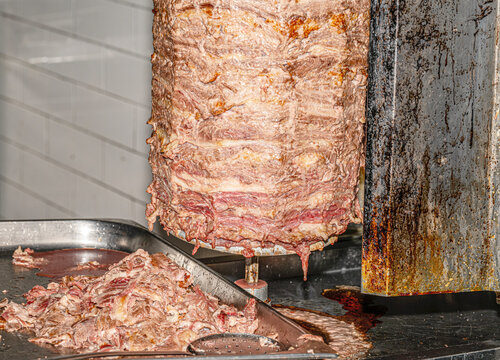  Close-up shot of a traditional Turkish d&ouml;ner kebab rotating on a vertical rotisserie spit at a street food market. [1] (https://www.shutterstock.com/search/d%C3%B6ner-kebap), [2] (https://www.shutter