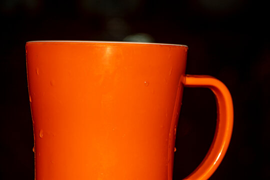 Orange cup featuring wet surface droplets for kitchen beverage use.