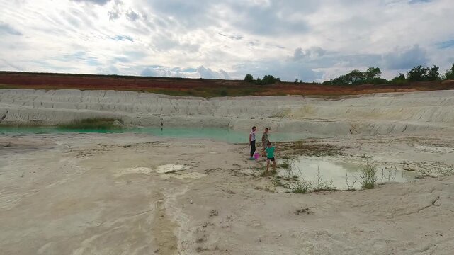 Wide view of an abandoned kaolin clay quarry featuring turquoise water, white clay slopes and a barren industrial landscape.