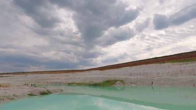 Scenic view of a turquoise quarry lake surrounded by white kaolin clay formations and exposed mineral-rich terrain.
