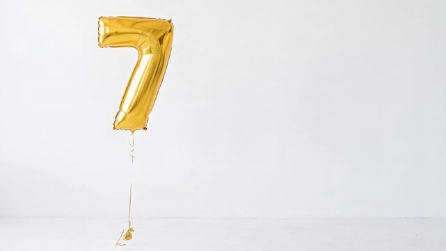 Large gold number seven helium balloon floating against a clean white background with generous copy space, ideal for seventh birthday, anniversary, milestone and celebration concepts